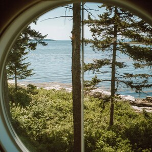 A view through a window of a natural landscape with trees and a body of water. - Sebasco Harbor Resort & Golf Club (Phippsburg)