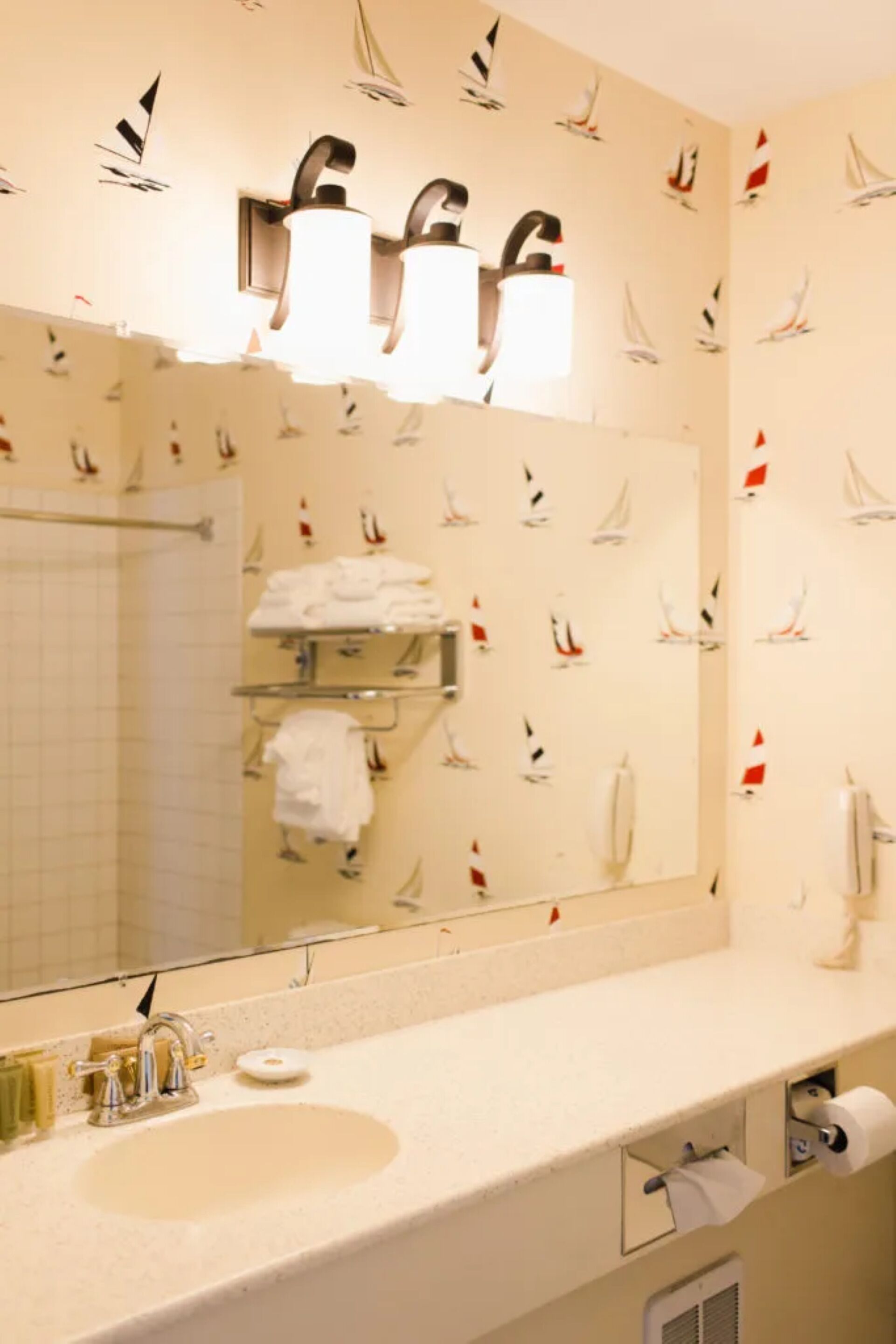 Un baño con un espejo grande, un lavabo y toalleros.