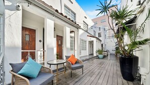 A wooden deck with wicker furniture and potted plants. - Chesterfield Hotel & Suites (Miami Beach)