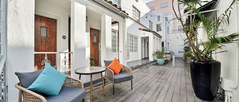A wooden deck with wicker furniture and potted plants.