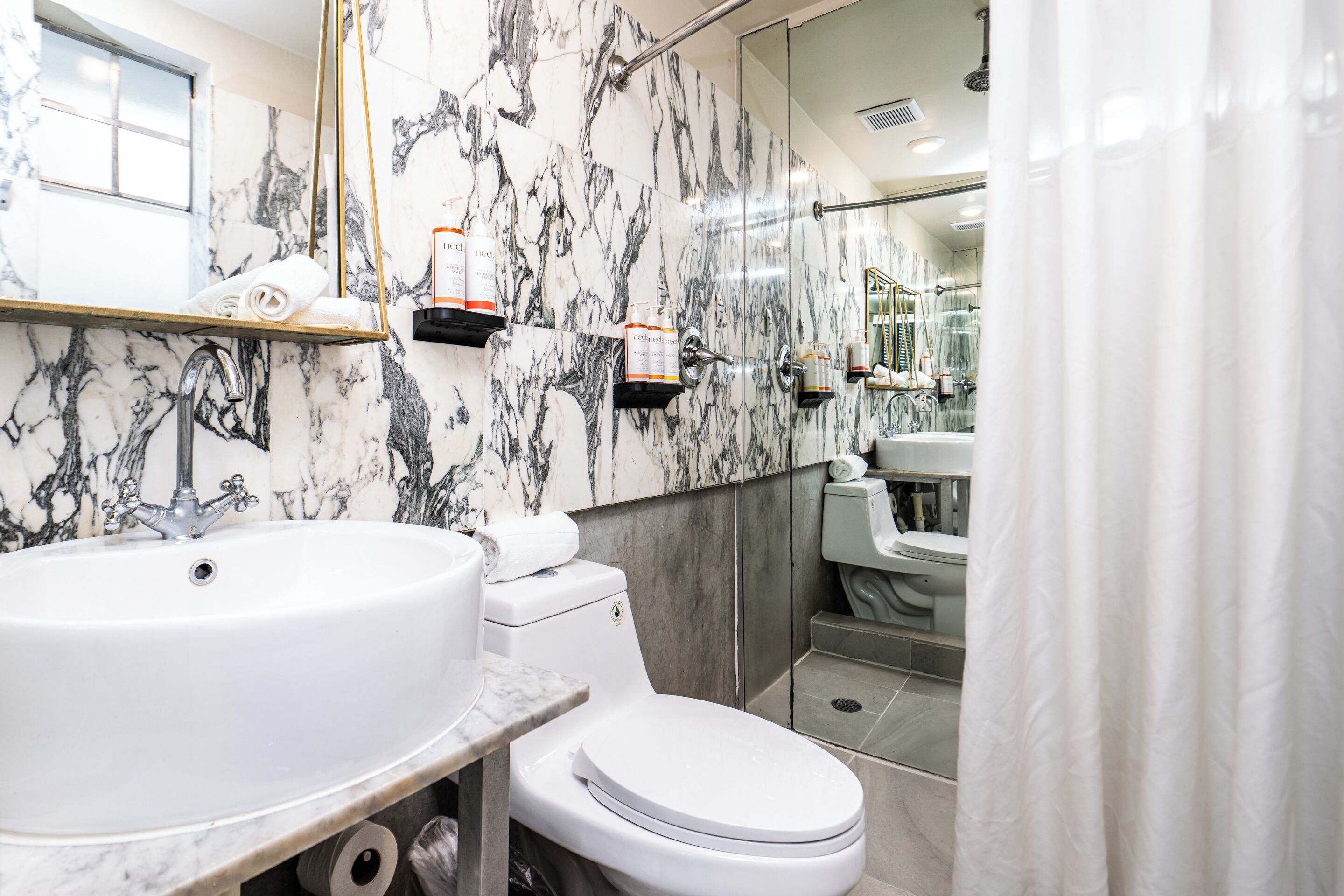 A bathroom with a marble sink, toilet, and shower.