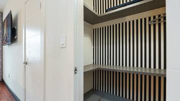 A corridor with a door, a wall-mounted television, and a striped wall.