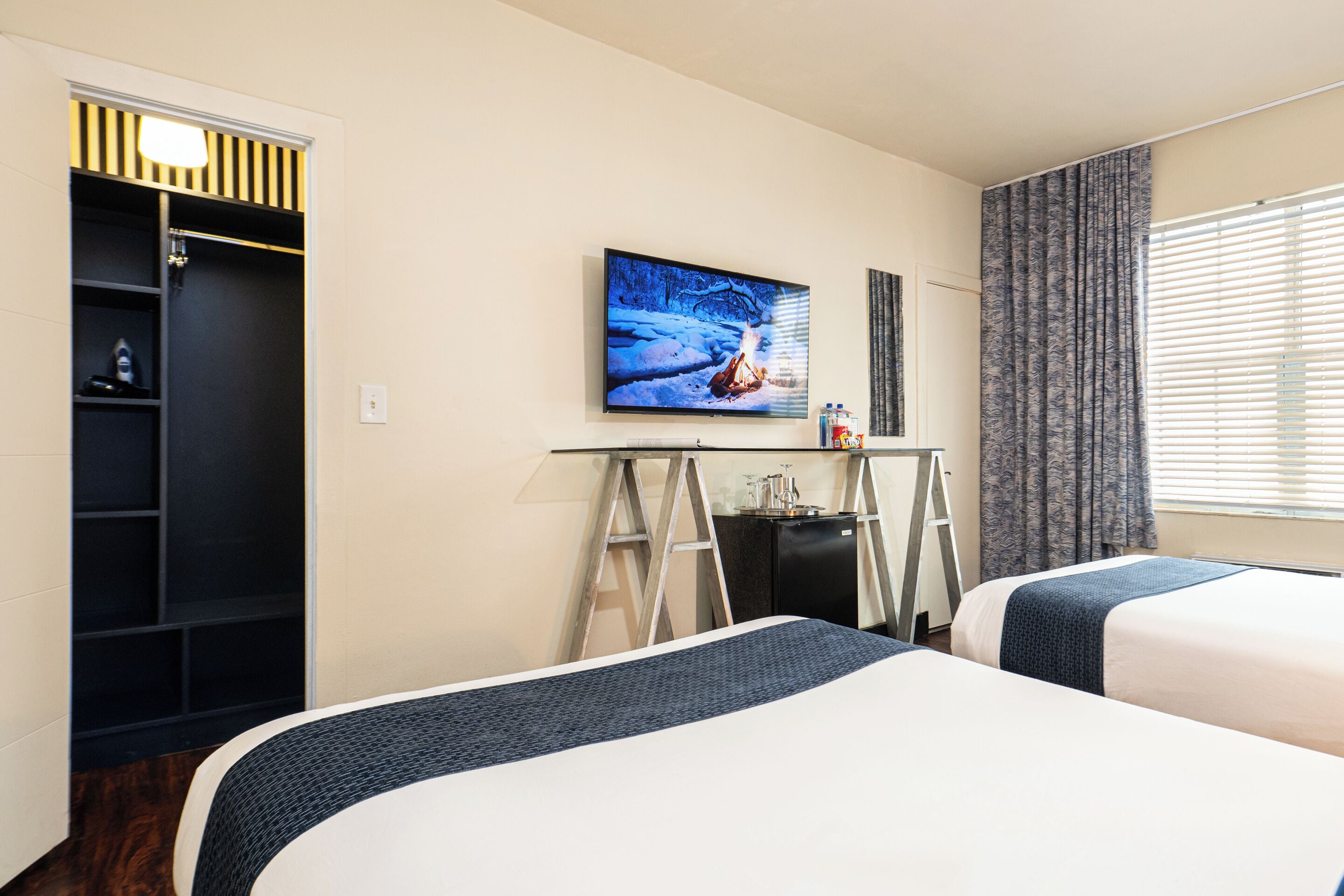 Une chambre d’hôtel avec deux lits, une télévision, un bureau et une armoire.