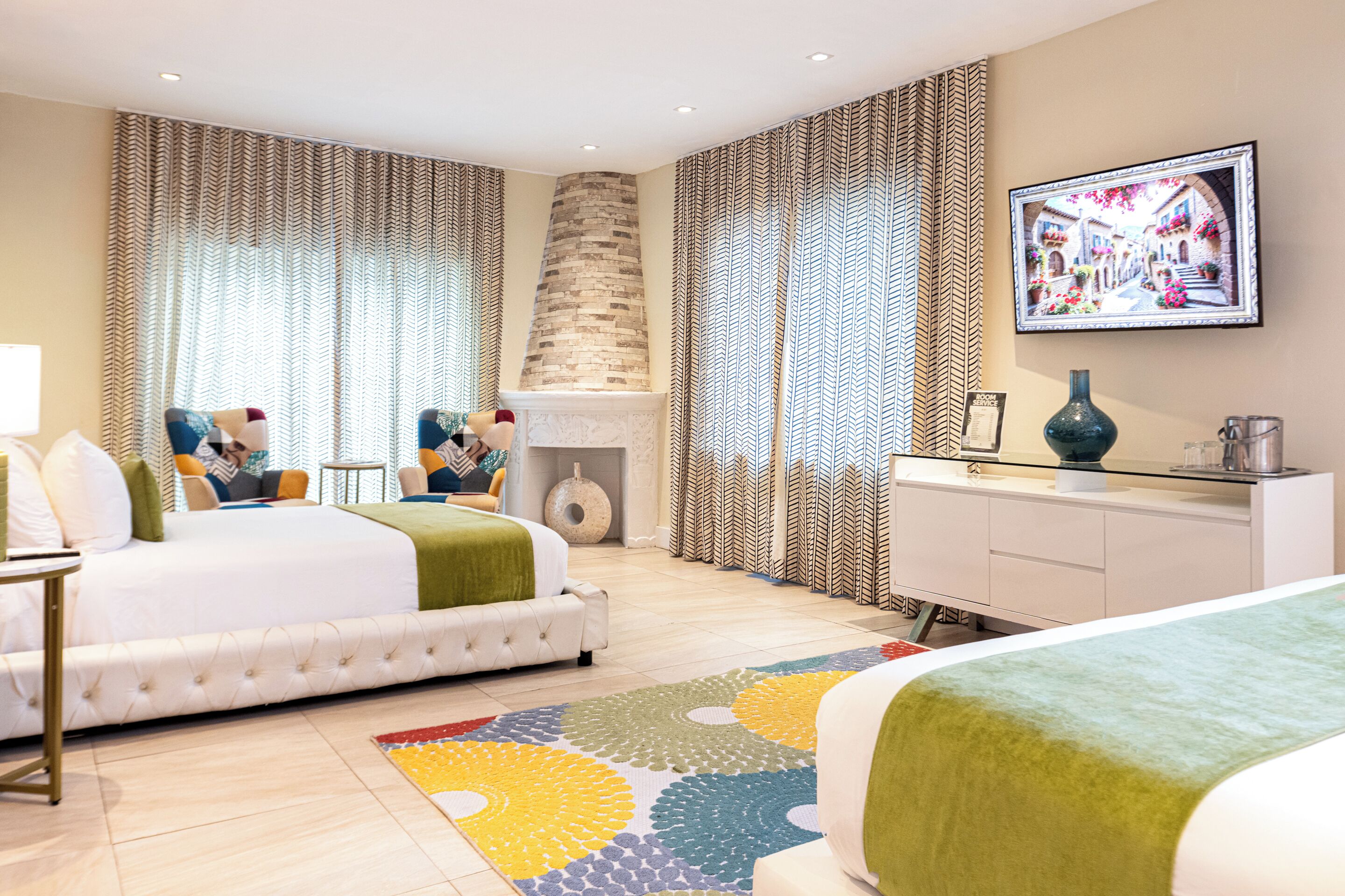 Ein modernes Hotelzimmer mit einem großen Bett, einer Couch, einem Schreibtisch und einem Kamin.