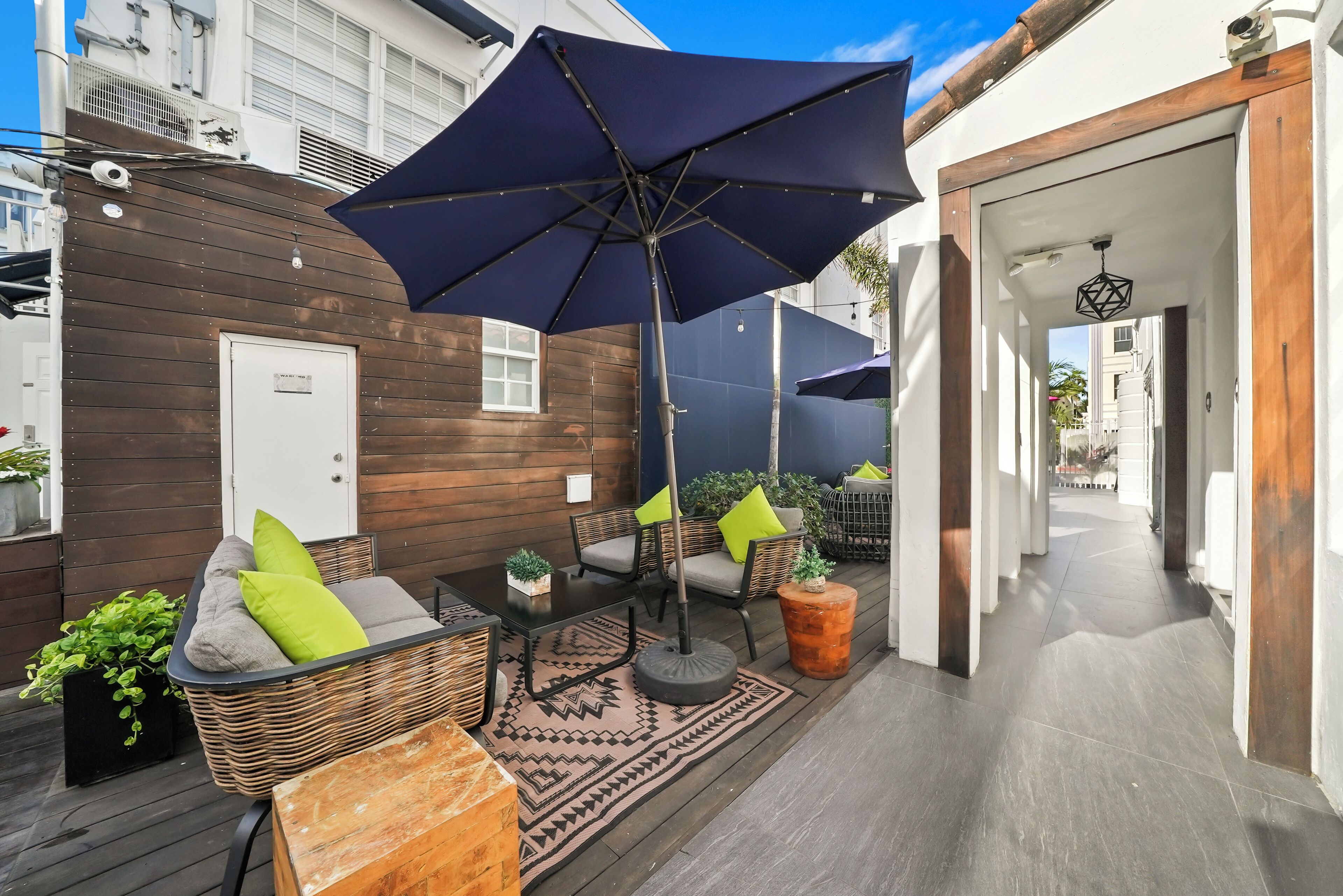 A patio area with wicker furniture, a large umbrella, and potted plants.