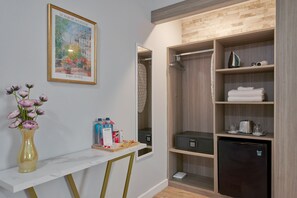 A hotel room with a marble-top desk, a vase of flowers, a mini bar, and a walk-in closet with shelves. - Hotel Shelley (Miami Beach)