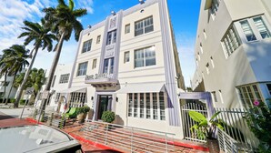 A hotel with a white facade, multiple windows, and a balcony.