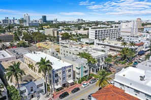 A cityscape with a mix of modern and older buildings, palm trees, and a clear sky. - Hotel Shelley (Miami Beach)