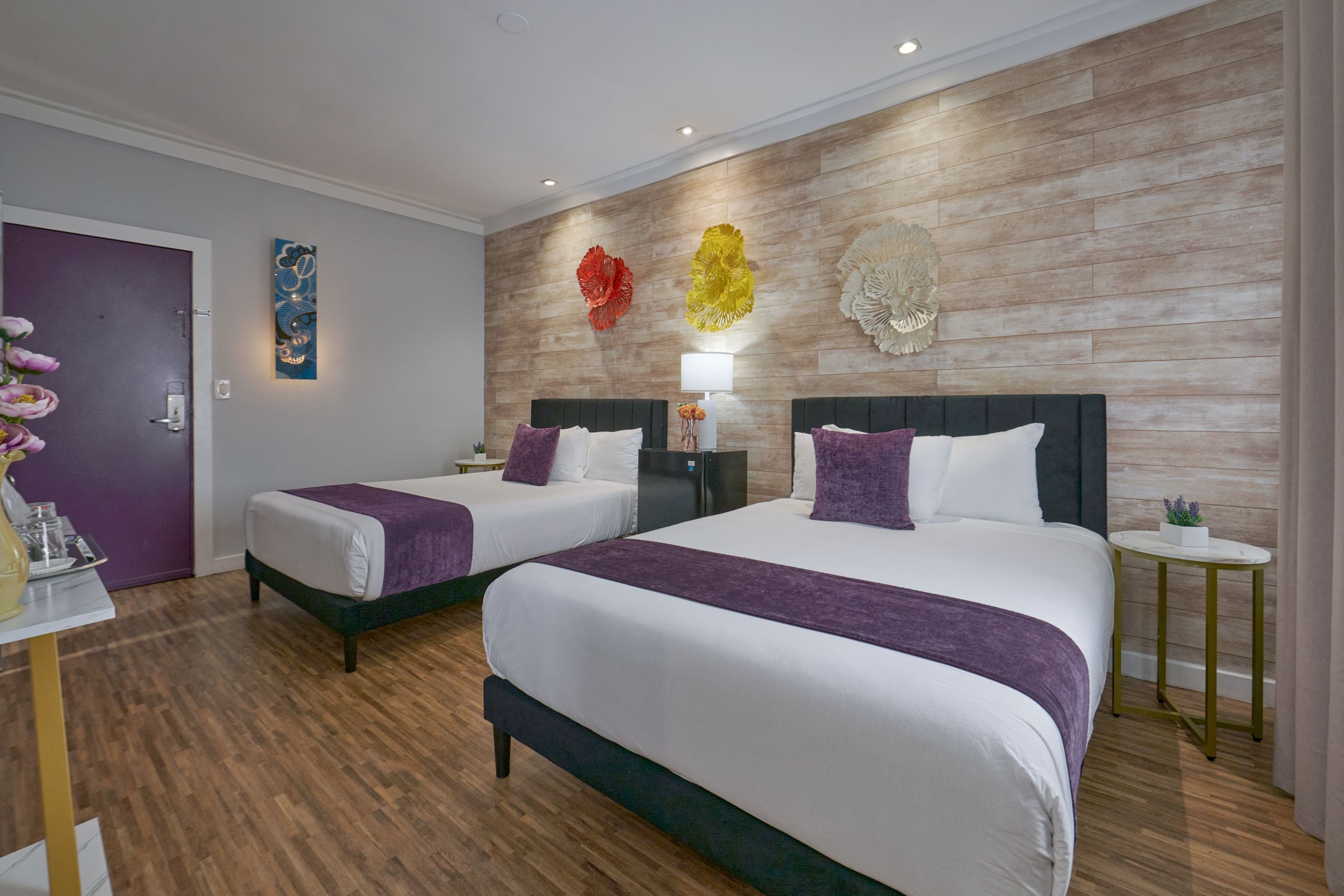 Habitació d'hotel amb dos llits, una paret de fusta i decoració mural.