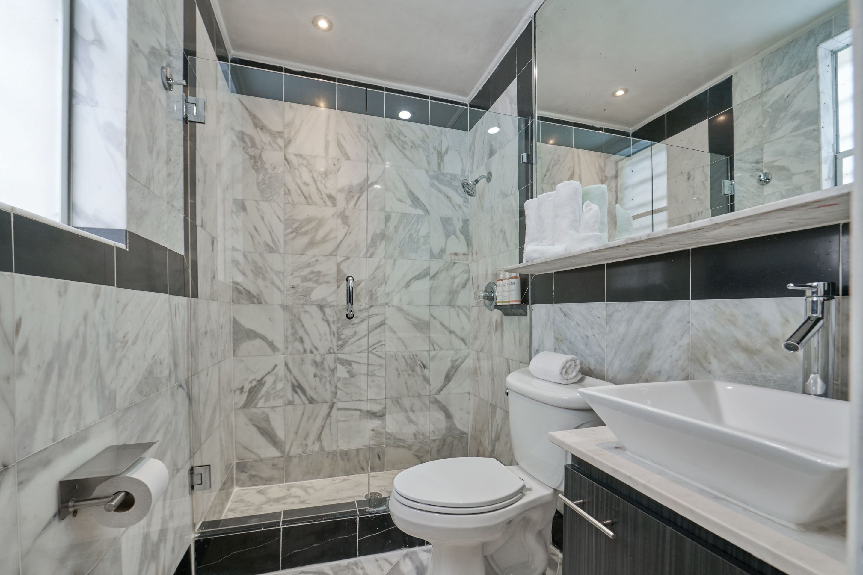 Un baño moderno con ducha, inodoro y lavamanos.