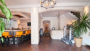 A spacious lobby with a bar area, a staircase, and a large potted plant.