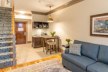 A room with a wooden coffee table, two leather armchairs, a floral-patterned sofa, and a painting of a landscape on the wall. at Andrew Pinckney Inn