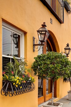 A round glass table with wicker chairs on a balcony, featuring breakfast items like croissants, muffins, and orange juice. at Andrew Pinckney Inn