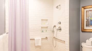A bathroom with a shower, toilet, and a framed picture on the wall.