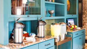 A kitchen with teal cabinetry, a granite countertop, and various kitchen appliances including a coffee maker and a kettle. - Andrew Pinckney Inn (Charleston)
