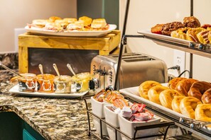 A buffet with various food items including sandwiches, pastries, and condiments.