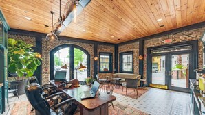 A spacious room with a wooden ceiling, a large desk with a laptop, leather chairs, and a large window with a view of the street. - Andrew Pinckney Inn (Charleston)