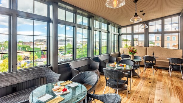 A modern interior with large windows, wicker furniture, and a wooden floor. - Andrew Pinckney Inn (Charleston)