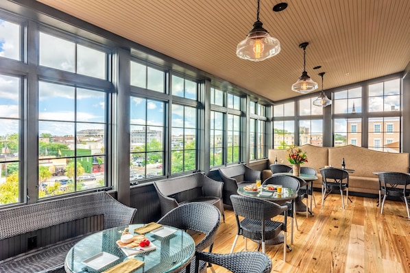 A modern interior with large windows, wicker furniture, and a wooden floor.