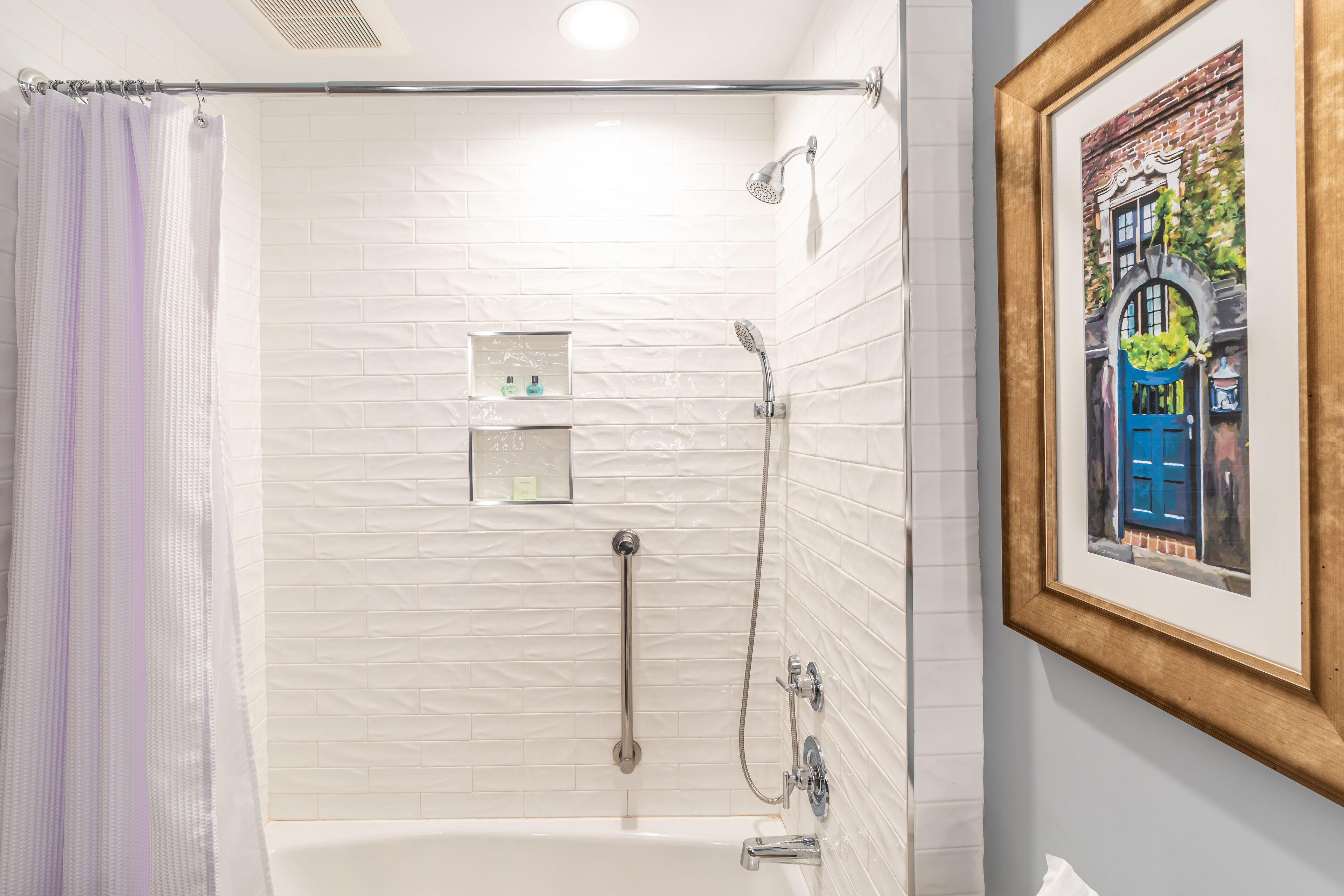 Ein modernes Badezimmer mit einer weißen Duschkabine, einer Badewanne und einem gerahmten Bild an der Wand.