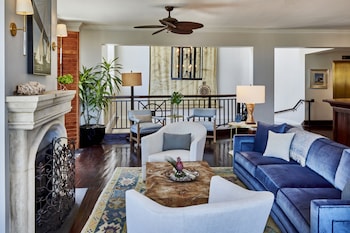 A dining area with two round tables, blue upholstered chairs, a buffet with various food items, and a framed painting on the wall. at HarbourView Inn
