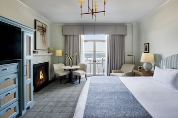 A spacious living room with a fireplace, comfortable seating, and a large window with a view. at HarbourView Inn