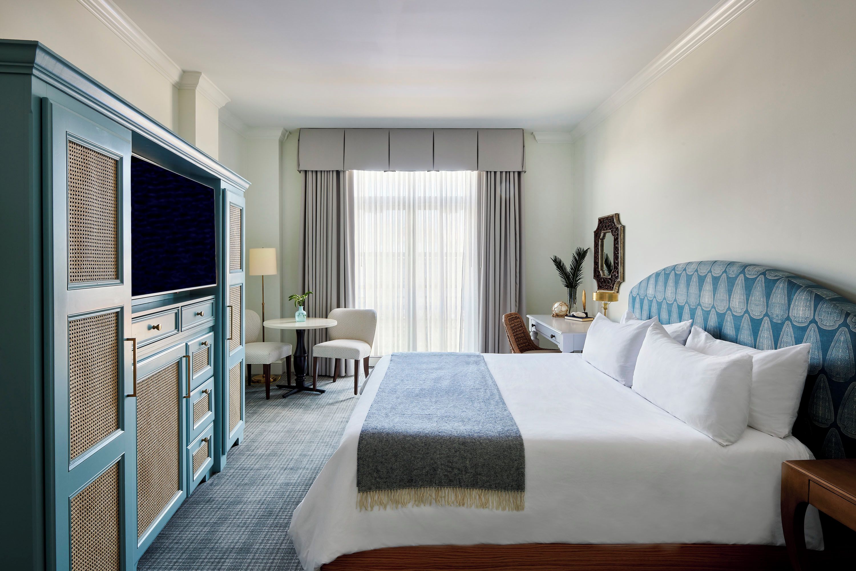 Une chambre d’hôtel avec un lit, un bureau, une chaise et une armoire.