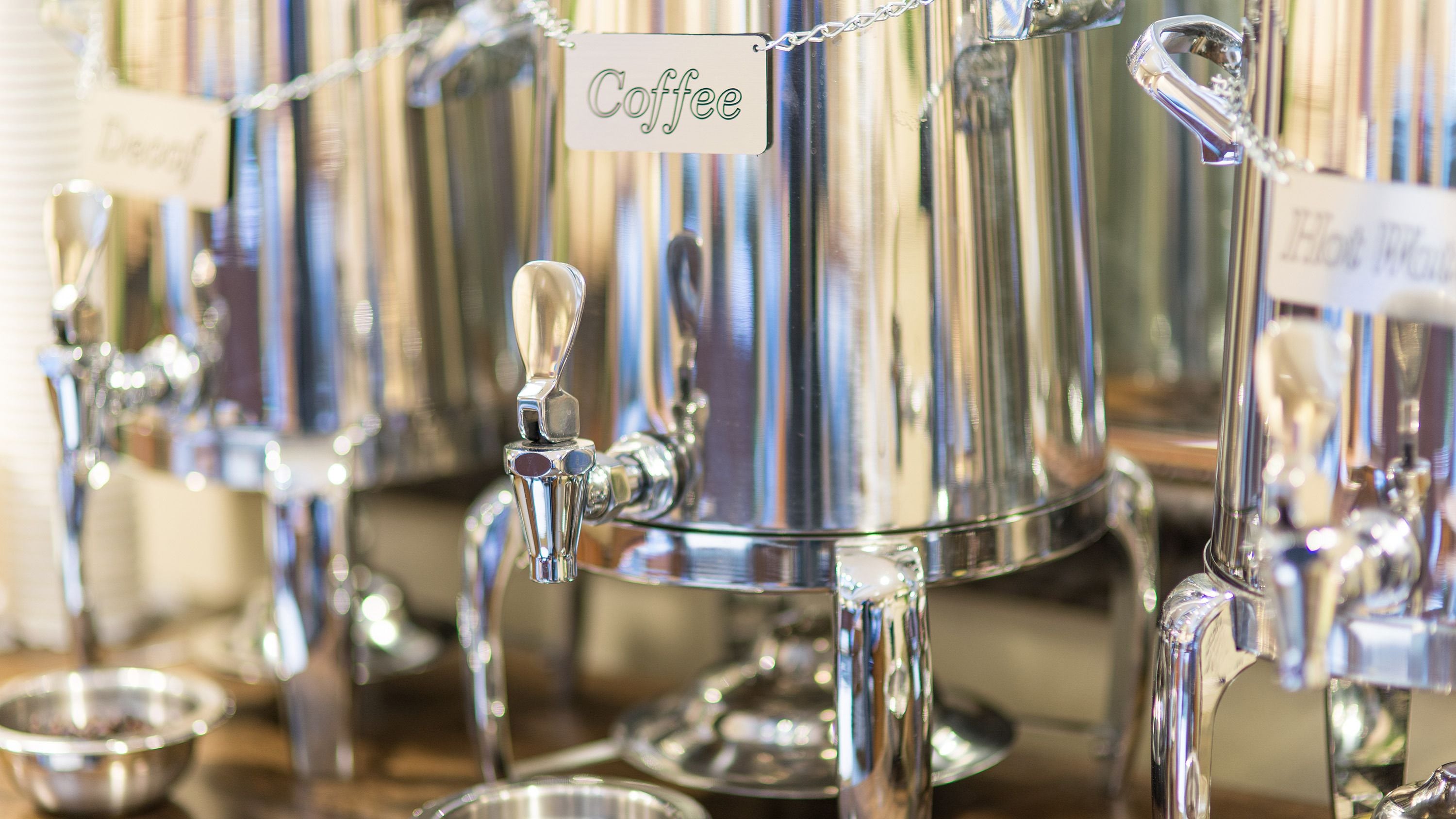 Un distributeur de café portant une étiquette indiquant le mot « Café », situé dans un établissement commercial.