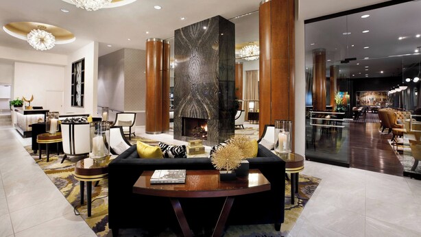 Een moderne hotellobby met een open haard, een zithoek en een eetgedeelte.