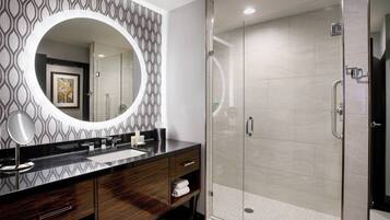 A modern bathroom with a large mirror, a glass-enclosed shower, and a patterned wall.