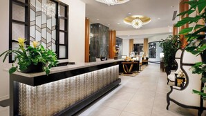 Een receptiegedeelte met een modern design, met een receptiebalie, potplanten en stijlvolle verlichtingsarmaturen.