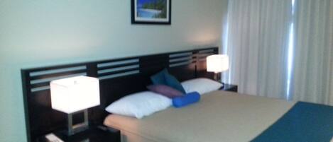 Una habitación de hotel con cama, mesitas de noche y un cuadro en la pared.