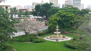 Un parc agrémenté d’une fontaine, entouré de pelouses et d’arbres bien entretenus.