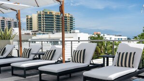 A rooftop lounge area with sun loungers and umbrellas, overlooking a cityscape with high-rise buildings. - Nassau Suite South Beach, an All-Suite Hotel (Miami Beach)
