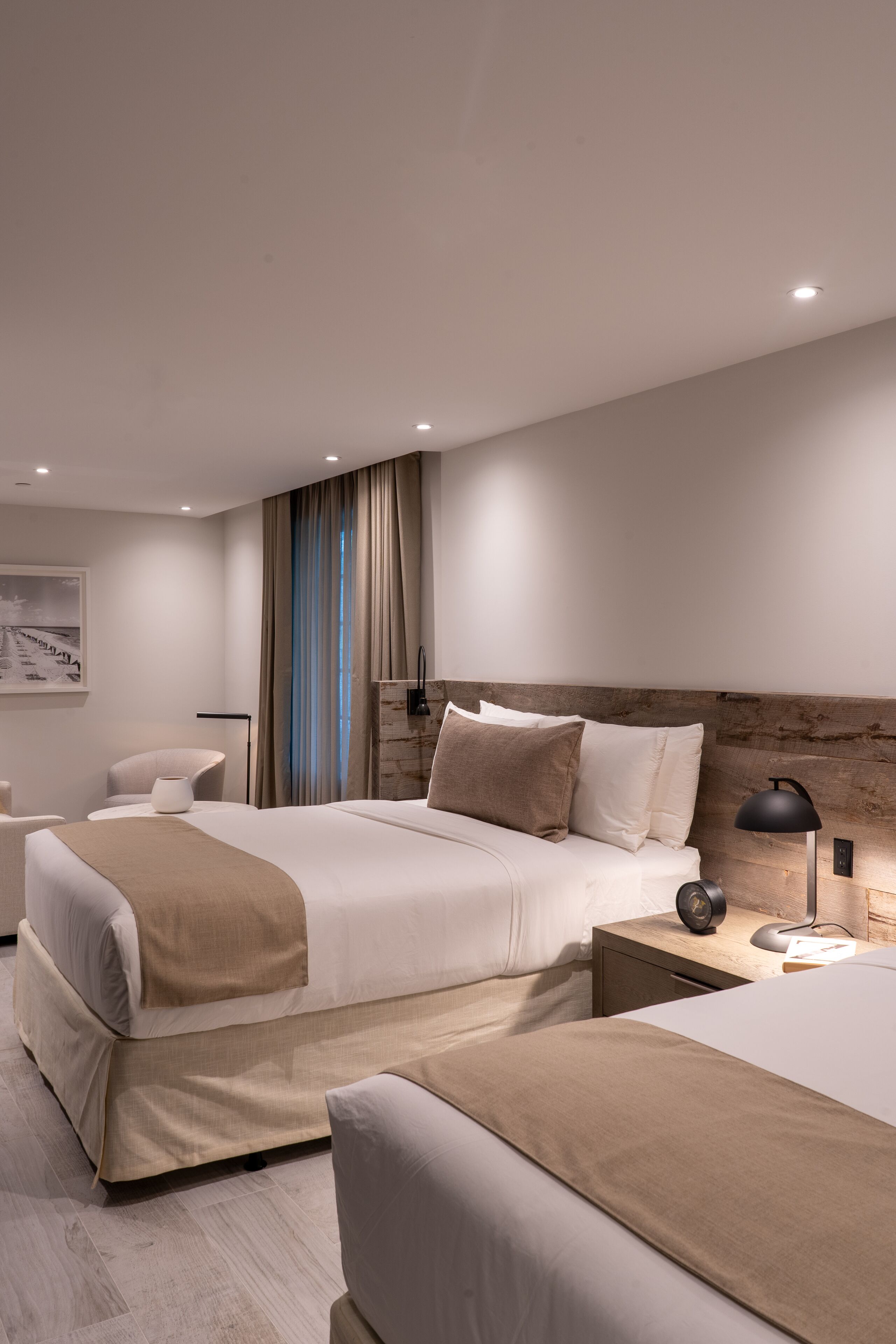 Una habitación de hotel moderna con una cama grande, una cama más pequeña, un escritorio y una silla.