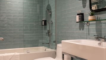 Une salle de bain avec une douche à parois de verre, des toilettes blanches et un lavabo surmonté d'un panier en osier.
