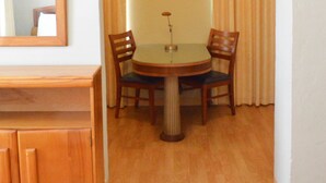 A dining area with a round table, two chairs, a wooden cabinet, and a painting on the wall. - Viscay Hotel (Miami Beach)