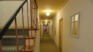 A hallway with carpeted stairs and a wooden handrail, leading to a door at the end. - Viscay Hotel (Miami Beach)