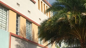 A building with a red and white facade, multiple windows, and a flag. - Viscay Hotel (Miami Beach)