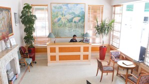 A reception area with a desk, chairs, a fireplace, and a large painting. - Viscay Hotel (Miami Beach)