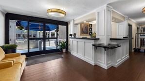 A modern hotel lobby with a reception desk, a yellow sofa, and a large glass door leading outside. - Comfort Inn Gaslamp Convention Center (San Diego)