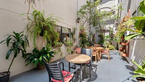A small outdoor patio area with a round table and chairs, surrounded by various potted plants and a small seating area. - Comfort Inn Gaslamp Convention Center (San Diego)