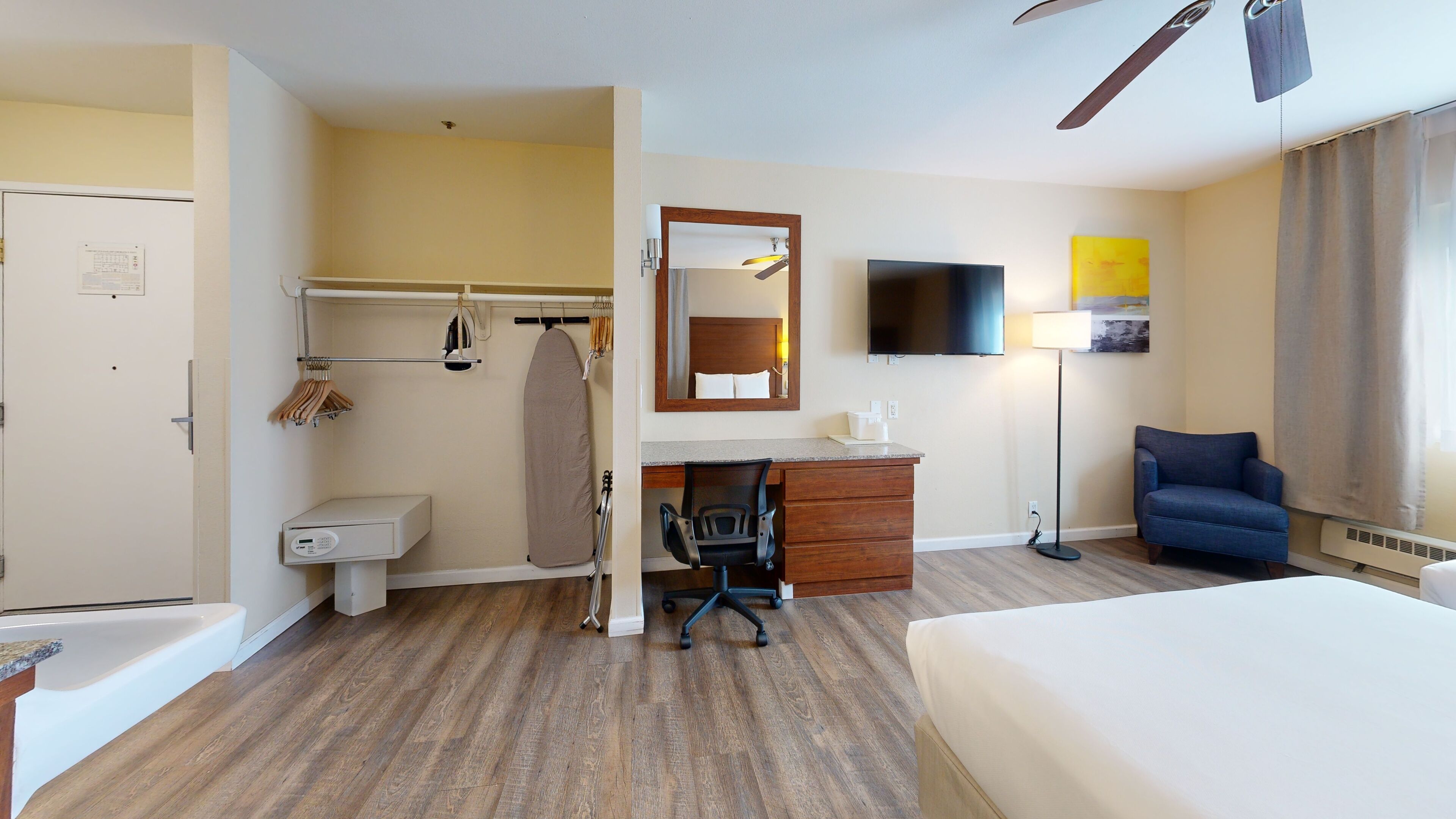 Una habitación de hotel con cama, escritorio, silla, tabla de planchar y televisor.