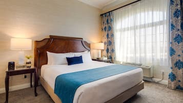 Habitación de hotel con una cama grande, dos mesitas de noche con lámparas, una ventana con cortinas y un calentador de pared.