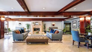 A spacious living room with two sofas, a coffee table, and a fireplace. - Ayres Suites Diamond Bar (Diamond Bar)