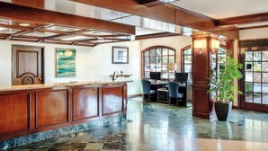A lobby with a reception desk, two chairs, a computer, and a potted plant. - Ayres Suites Diamond Bar (Diamond Bar)