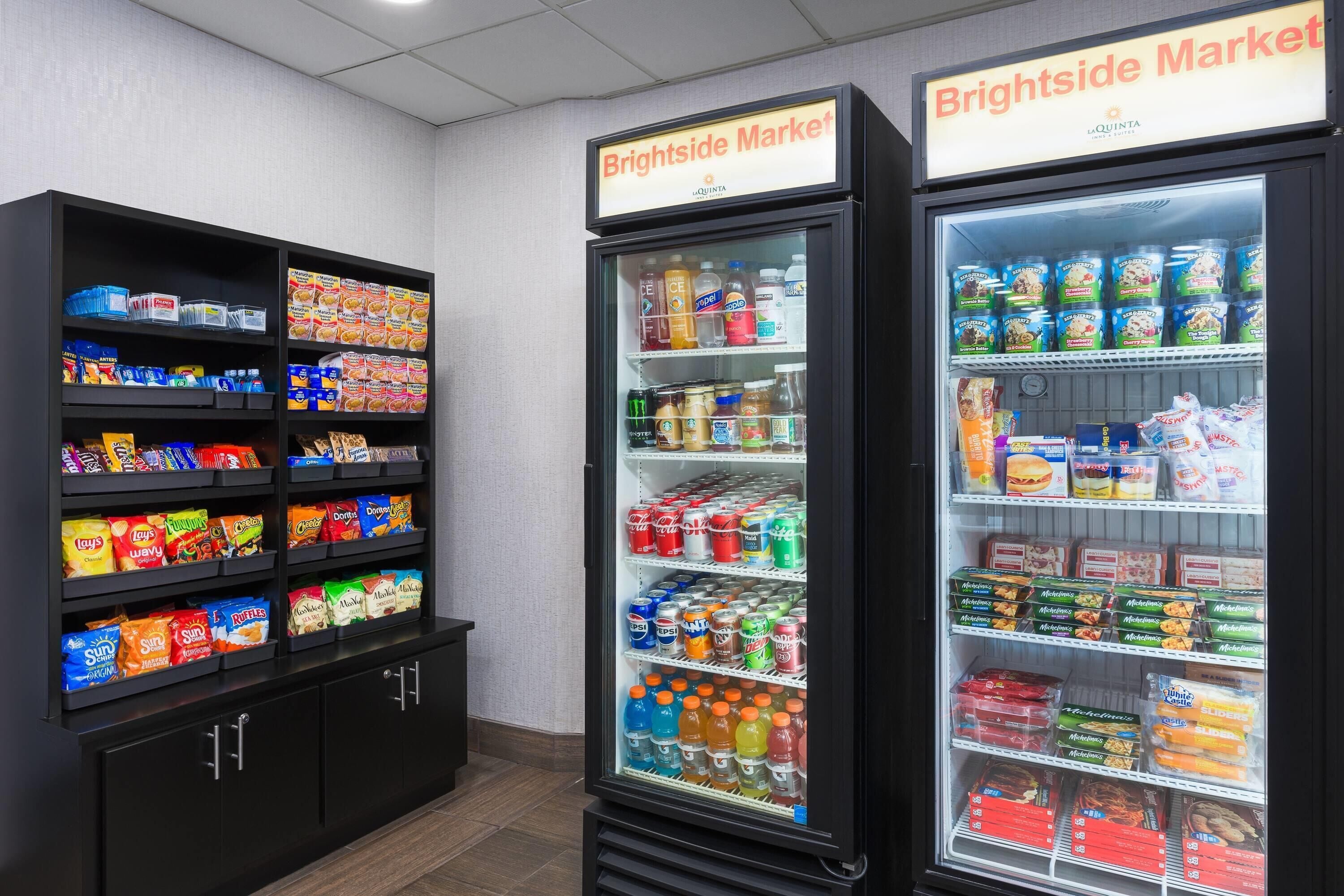 Un enfriador refrigerado con diversos alimentos y una estantería con aperitivos.