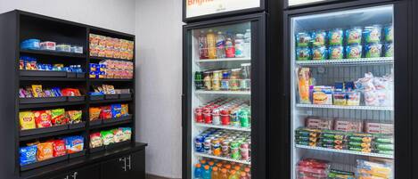 Un enfriador refrigerado con diversos alimentos y una estantería con aperitivos.