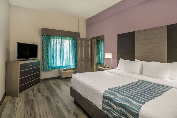 Una habitación de hotel con cama, televisión, escritorio y ventana con cortinas.