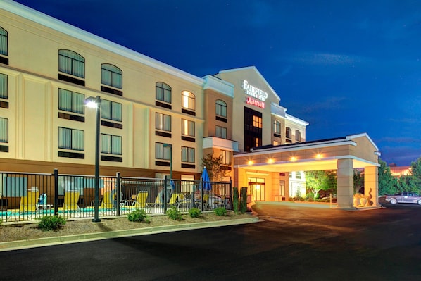 Un hotel Fairfield Inn & Suites by Marriott con una entrada bien iluminada, zona de estar al aire libre y aparcamiento.